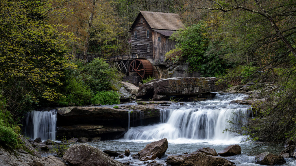 waterfall long exposure near an old wooden grist mill in a forest setting